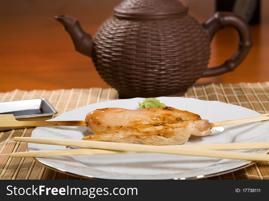 Hot barbecued chicken fillet as closeup on a white plate