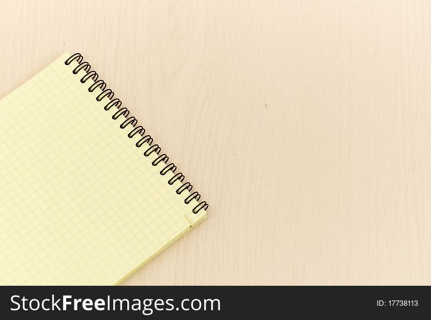 Yellow note book with lots of room for your text or image on a wooden desk