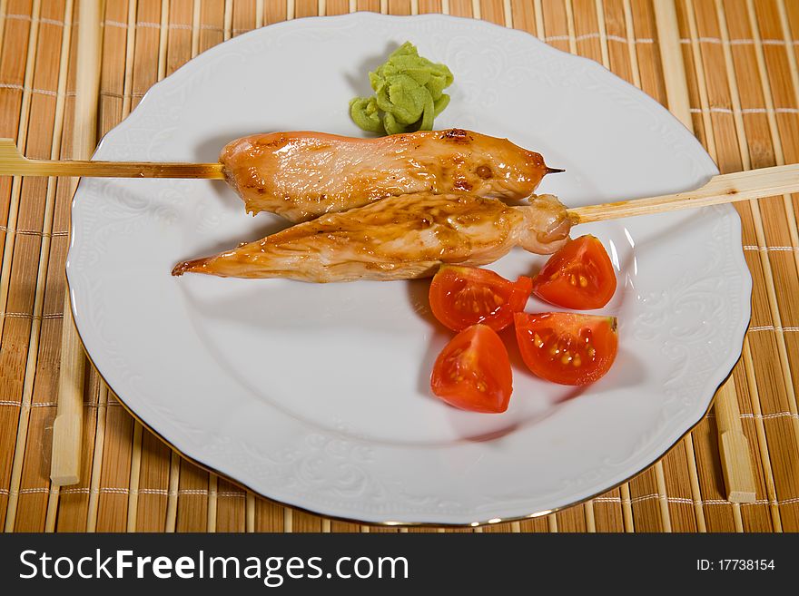 Hot barbecued chicken fillet as closeup on a white plate