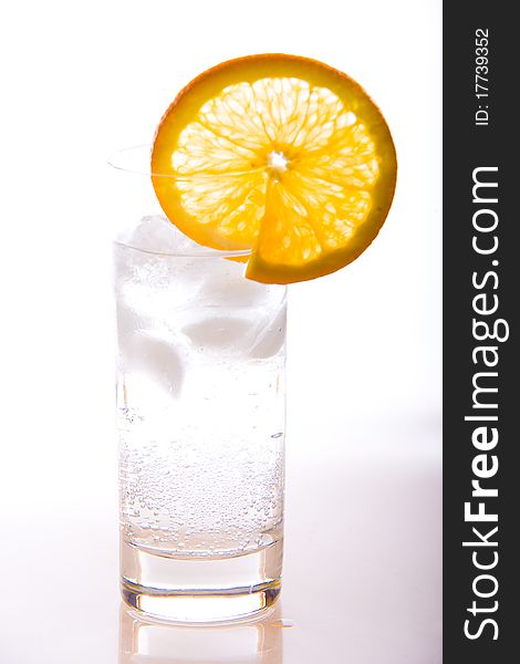 Isolated glass of soda with ice cold water on a white background with orange slice