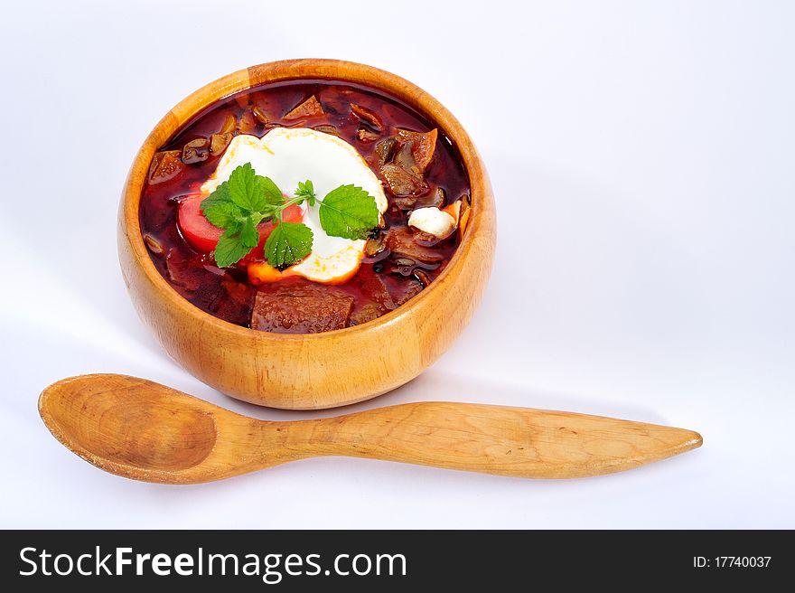 Soup with sour cream in wood plate with spoon