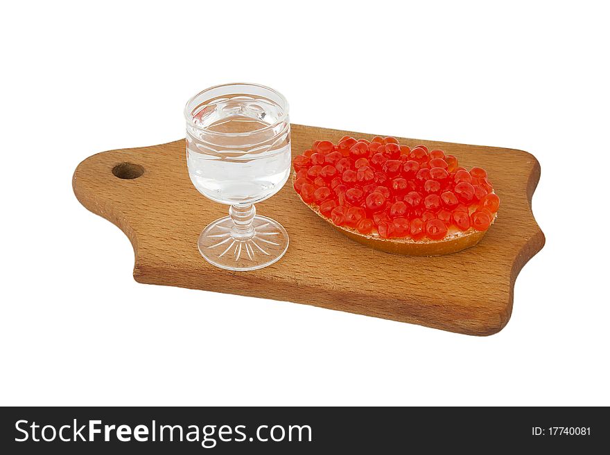 Bread with red caviar and glass of vodka on wooden plank