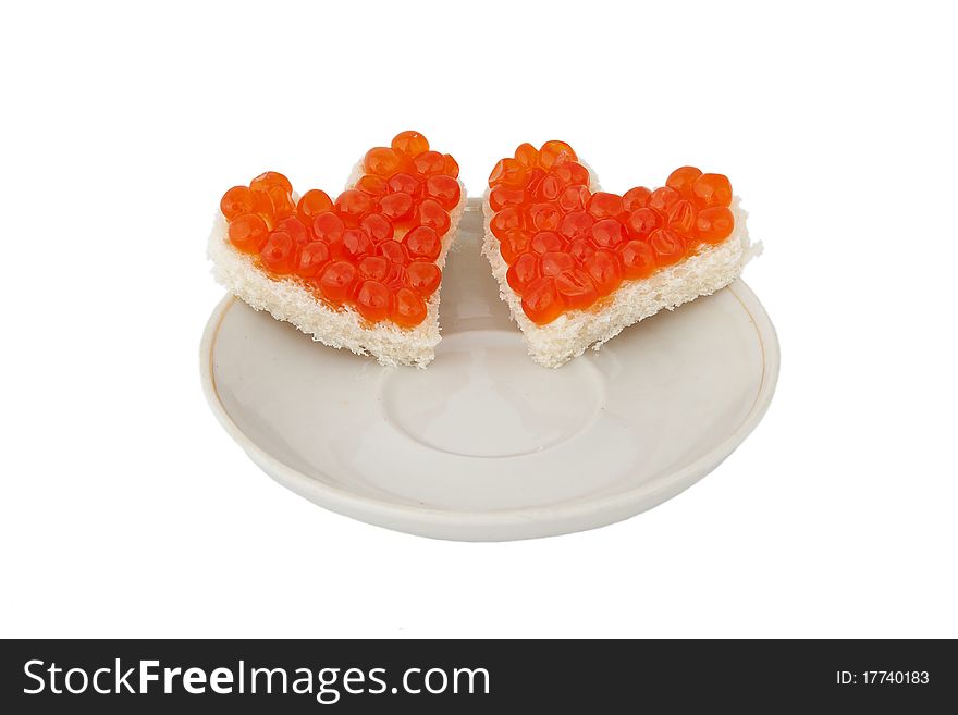 Two pieces of bread in the form of a heart with red caviar on plate on white background. Two pieces of bread in the form of a heart with red caviar on plate on white background