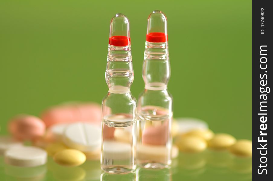 Macro ampoule and pills shot on green background