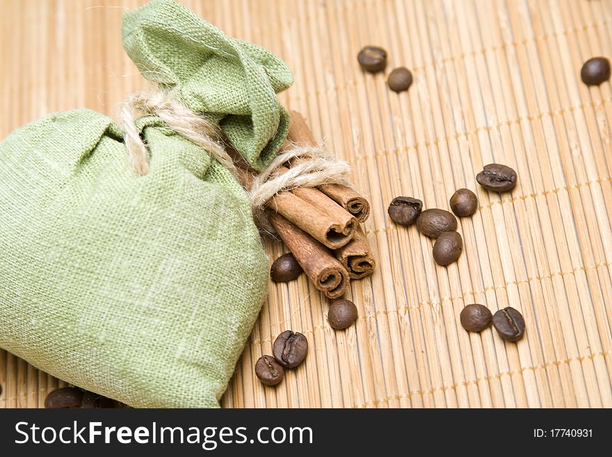 Coffee beans and cinnamon sticks in canvas sack on wooden background. Green bag. Coffee beans and cinnamon sticks in canvas sack on wooden background. Green bag