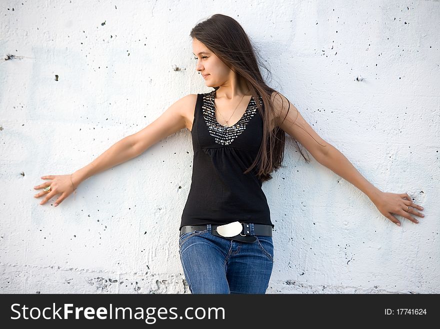 Beautiful Asian girl in jeans on a background of white stone wall