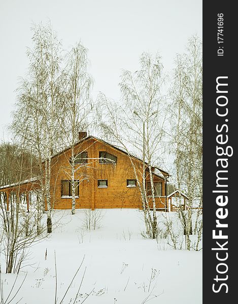 Cottage or chalet of stained wood, wooden house, residential structure, residential district, construction timber, prefabricated buildings with double glazing, winter trees, snow, white and brown, vertical. Cottage or chalet of stained wood, wooden house, residential structure, residential district, construction timber, prefabricated buildings with double glazing, winter trees, snow, white and brown, vertical