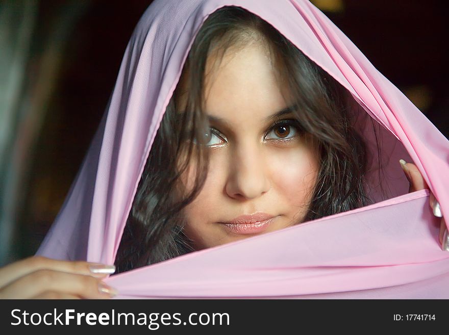 Beautiful Asian girl in a pink shawl looks into the camera