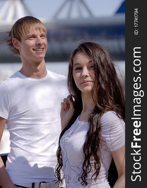 Two fashionable and trendy teenagers against the blue sky and skyscrapers (modern buildings)