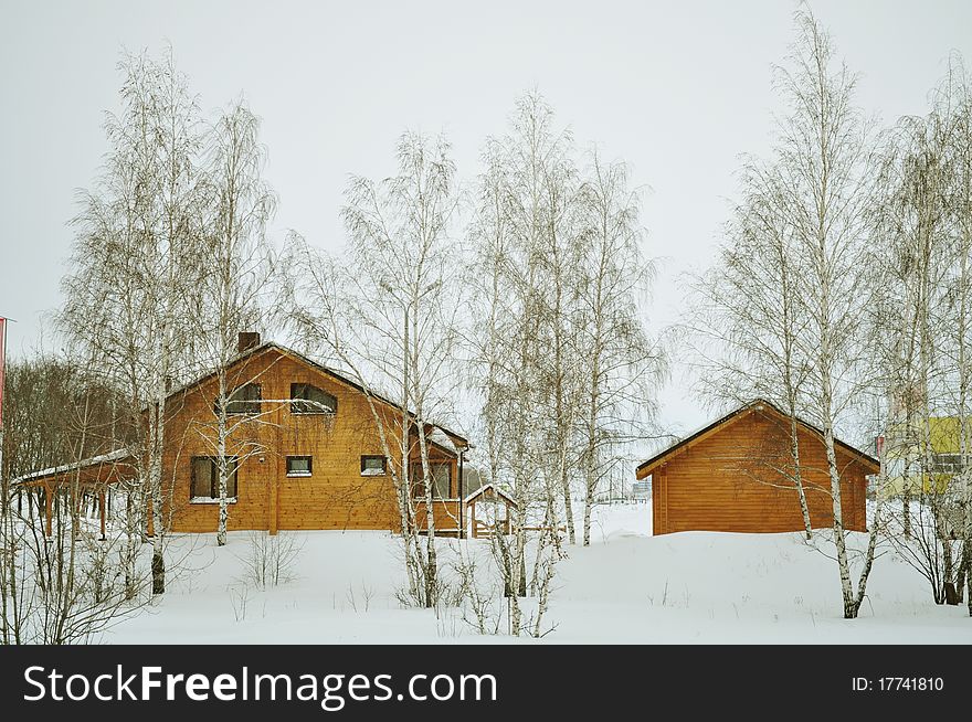 Suburb, cottage or chalet of stained wood, luxury house, residential structure, residential district, construction timber, prefabricated buildings with double glazing, winter trees, snow, white and brown. Suburb, cottage or chalet of stained wood, luxury house, residential structure, residential district, construction timber, prefabricated buildings with double glazing, winter trees, snow, white and brown