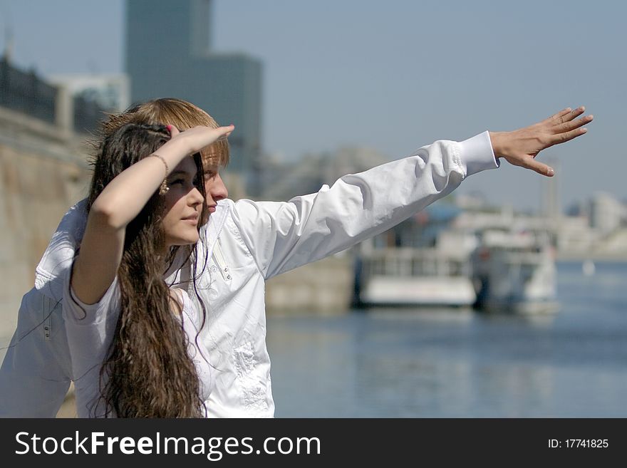 Two fashionable and trendy teenagers against the blue sky and skyscrapers (modern buildings)