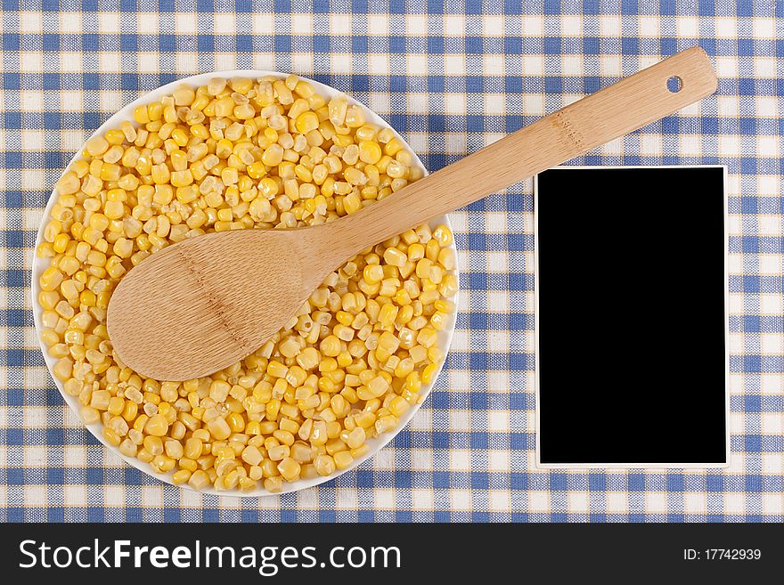 Canned corn in a white plate against the checkered background.