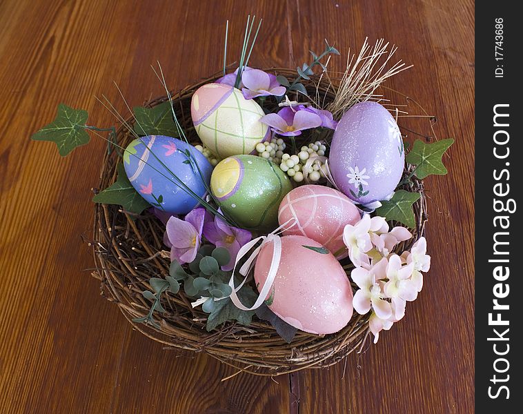 Painted Easter eggs in nest with flowers and overview on a wooden table. Painted Easter eggs in nest with flowers and overview on a wooden table