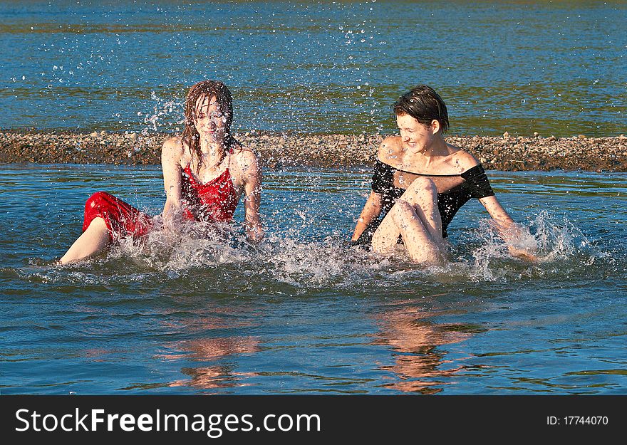 Two girls plays the fool in the river in summer. Two girls plays the fool in the river in summer