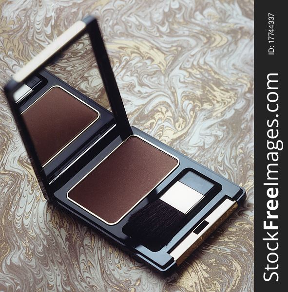 Open face powder with mirror isolated on brown gold and gray background