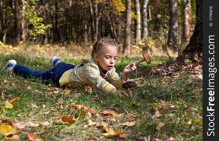 A smiling girl is laying on a grass in the forest. A smiling girl is laying on a grass in the forest