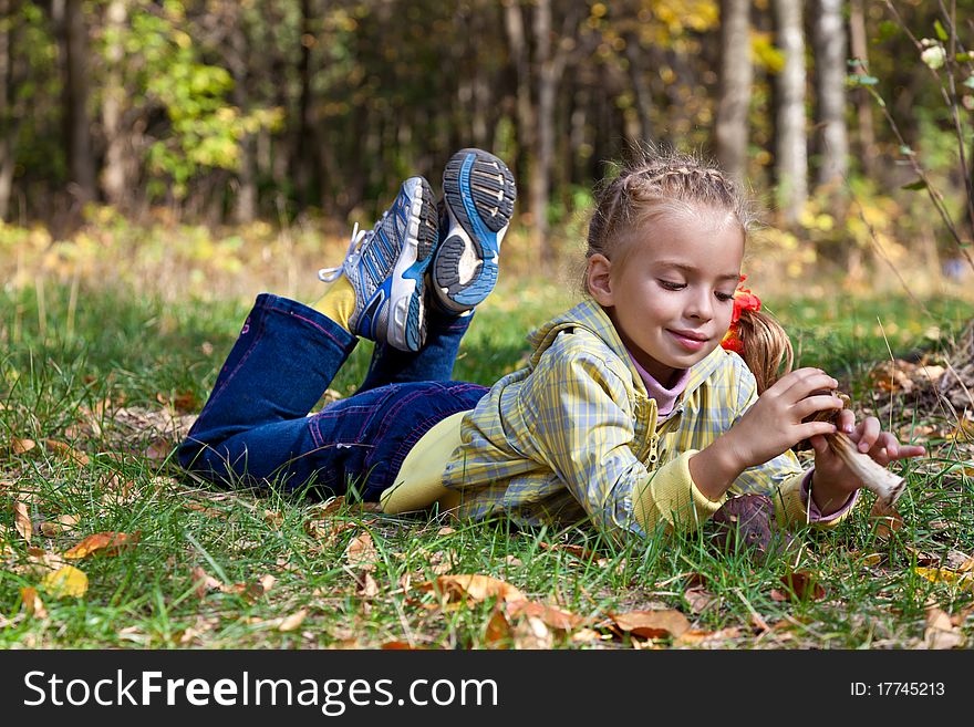 A smiling girl is laying on a grass in the forest. A smiling girl is laying on a grass in the forest