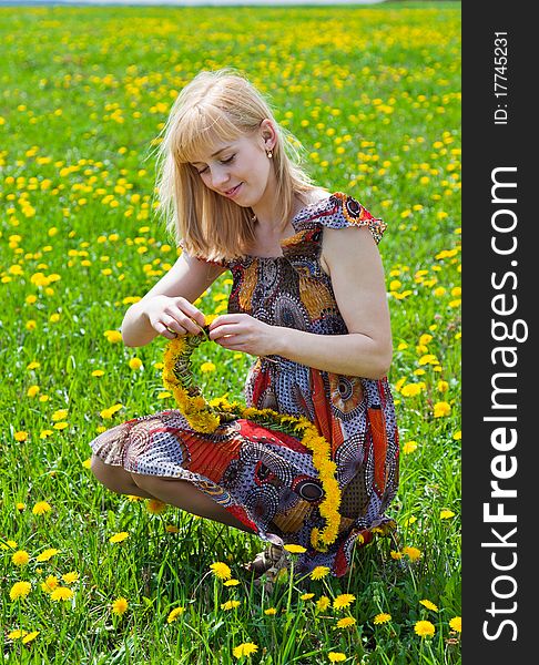 A smiling woman is sitting on a field. A smiling woman is sitting on a field