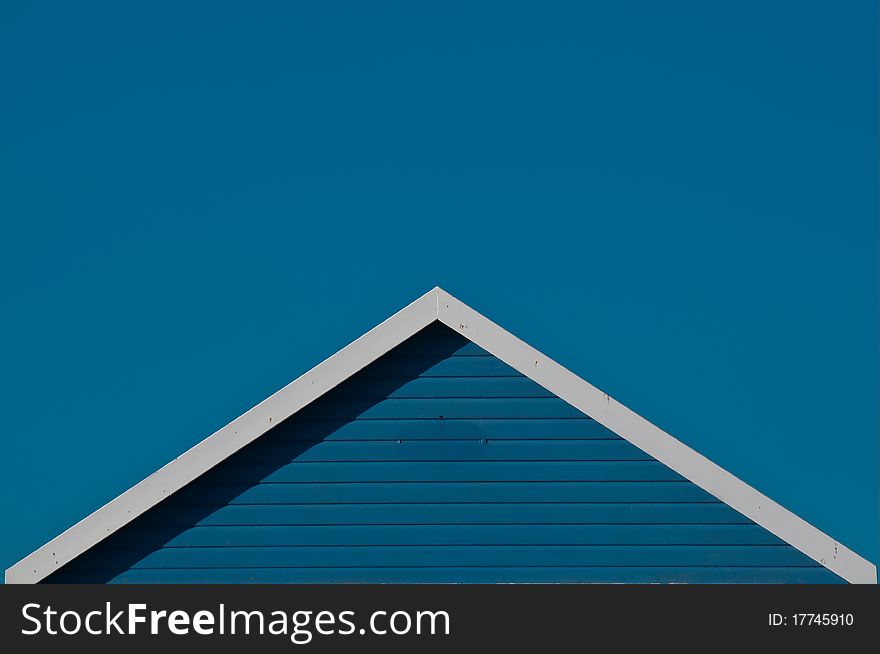 Triangle detail of blue beach hut gable against deep blue summer sky. Triangle detail of blue beach hut gable against deep blue summer sky