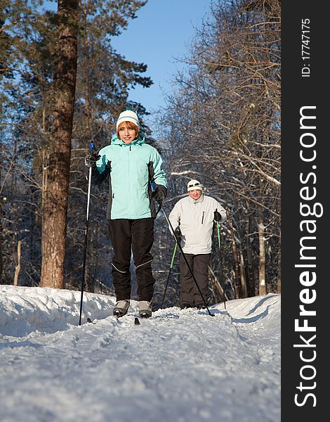 Man And Woman Walk On Ski In Winter Forest