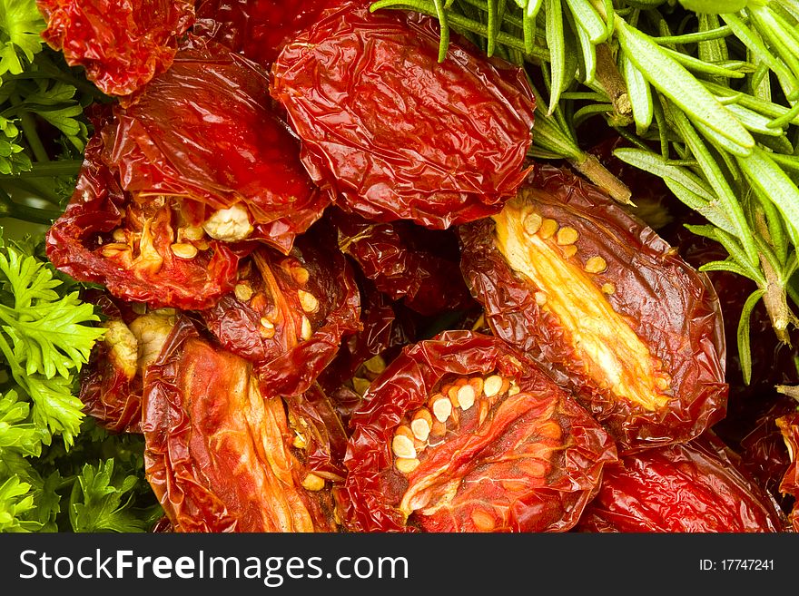 Ripe red sun-dried plum tomatoes with fresh rosemary leaves and green parsley. Ripe red sun-dried plum tomatoes with fresh rosemary leaves and green parsley