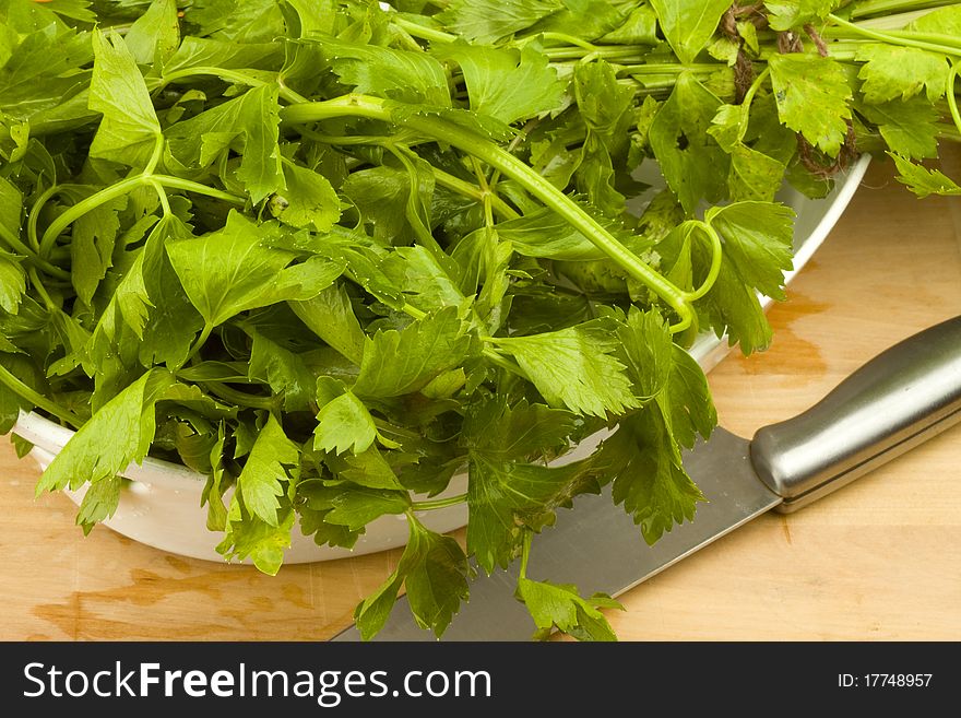 Freshly cut celery leaves on a wooden table with a cutting knife. Freshly cut celery leaves on a wooden table with a cutting knife