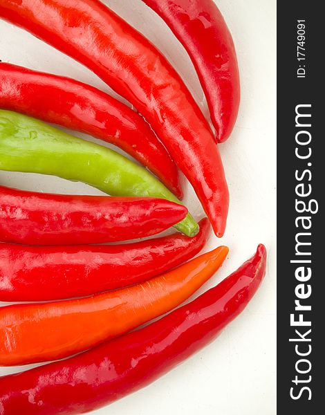 A colorful row of red and green spicy chili peppers on white background