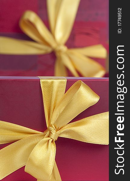 Red gift boxes with yellow ribbons , one blurred behind. Red gift boxes with yellow ribbons , one blurred behind