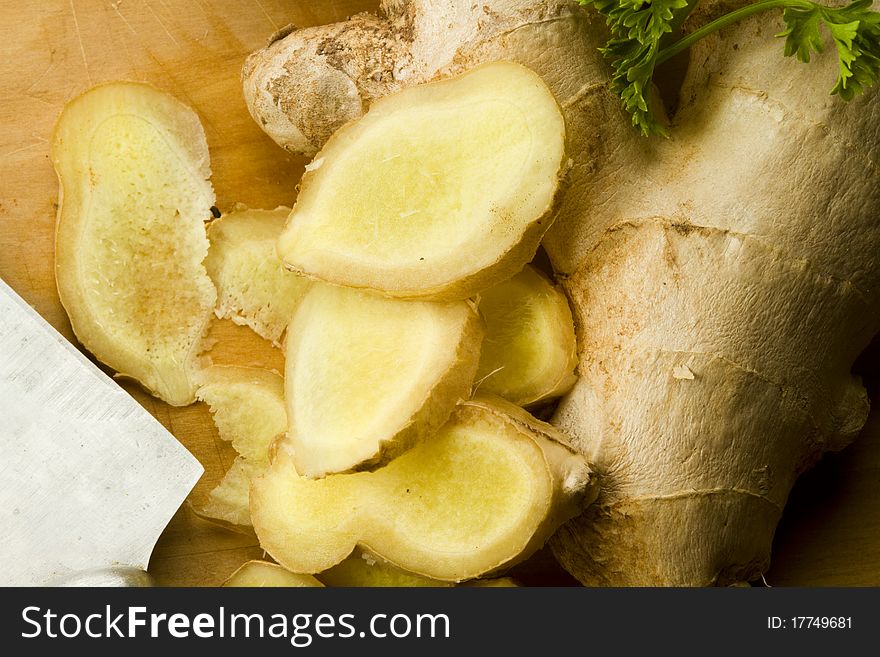 Freshly cut ginger rhizome with garden parsley leaves on a wooden surface