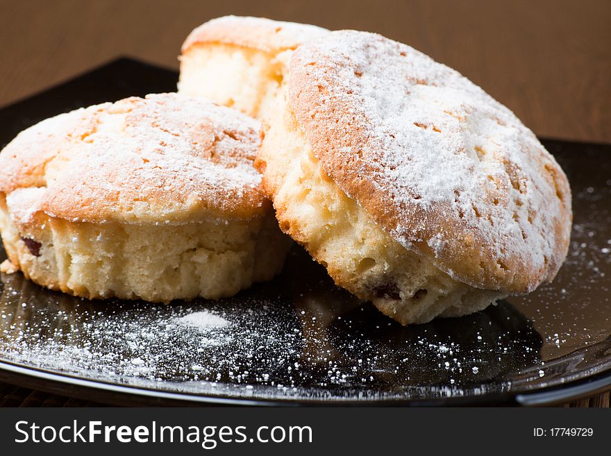 Muffins with a sugar powder on a black plate