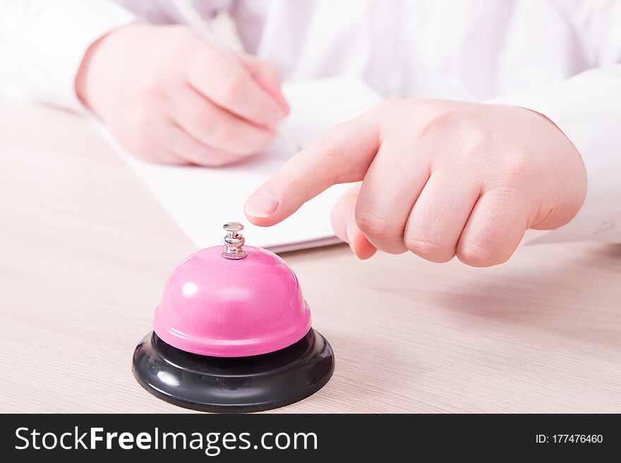 A man in a white shirt presses a finger on a pink service bell and signs a contract, a legal employment contract in the service sector, a job search in the hotel, restaurant, hire employees