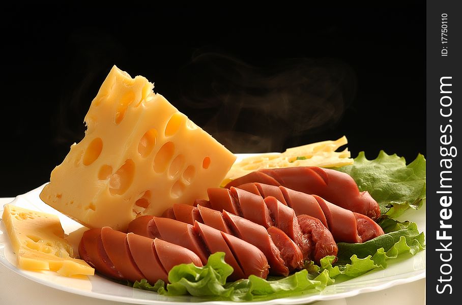 Sausages with cheese on plates are decorated by salad