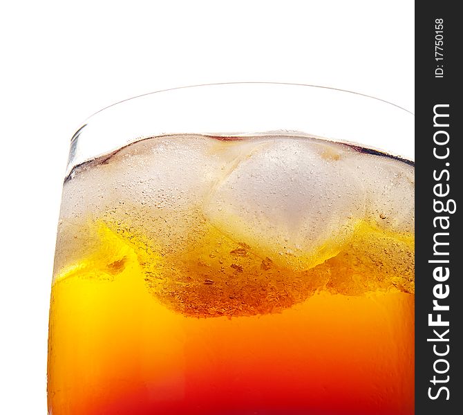 Closeup of fresh cold orange drink in a glass with ice and air bubbles