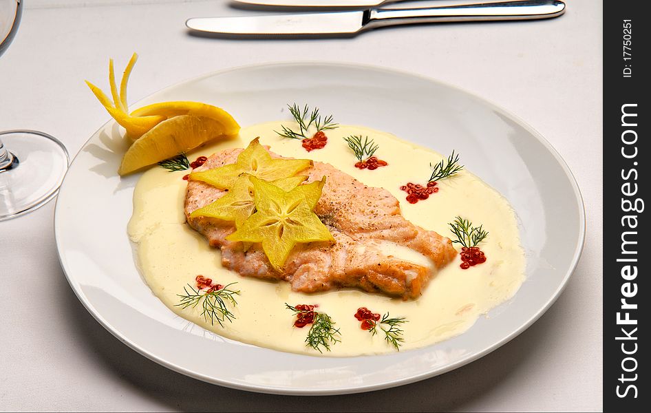 Fish a salmon fried with creamy sauce decorated with red caviar on a plate. Fish a salmon fried with creamy sauce decorated with red caviar on a plate