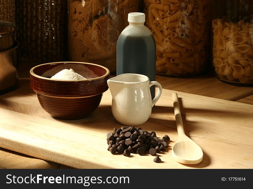 Baking ingredients on wooden counter top with jars of cooking ingredients in the background. Baking ingredients on wooden counter top with jars of cooking ingredients in the background