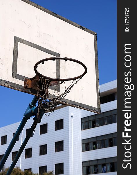 Outdoor basketball hoop against blue sky at an old school