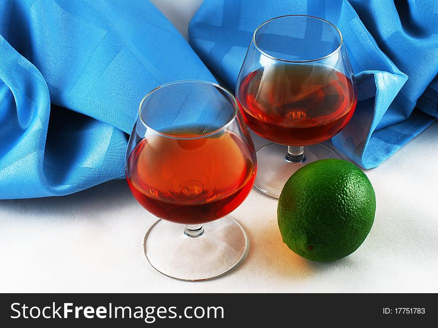 Two glasses of brandy and lime on white background