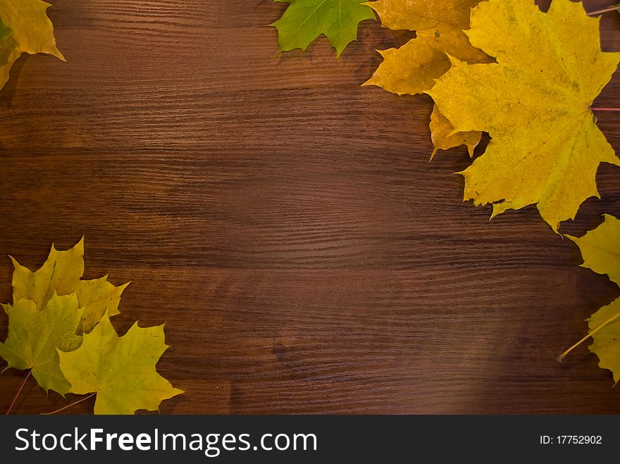 A frame from marple leaves over wooden desk. A frame from marple leaves over wooden desk