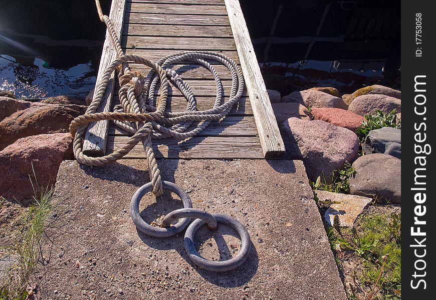 Classical anchoring point made of cast iron in a port marina / nautical background horizontal image. Classical anchoring point made of cast iron in a port marina / nautical background horizontal image