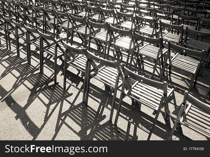 Lots of wooden chairs standing in a row. Monochrome image.