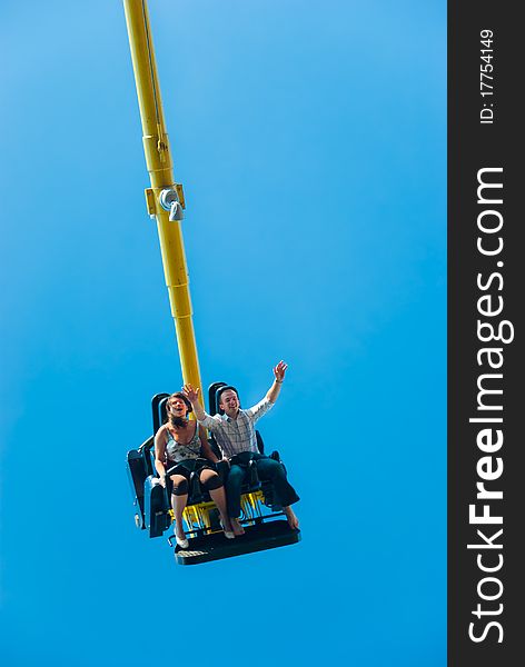 Happy young couple riding on the attraction