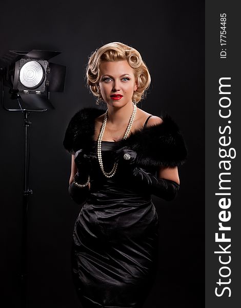 Young blonde woman with fur and necklace on a black background. Young blonde woman with fur and necklace on a black background