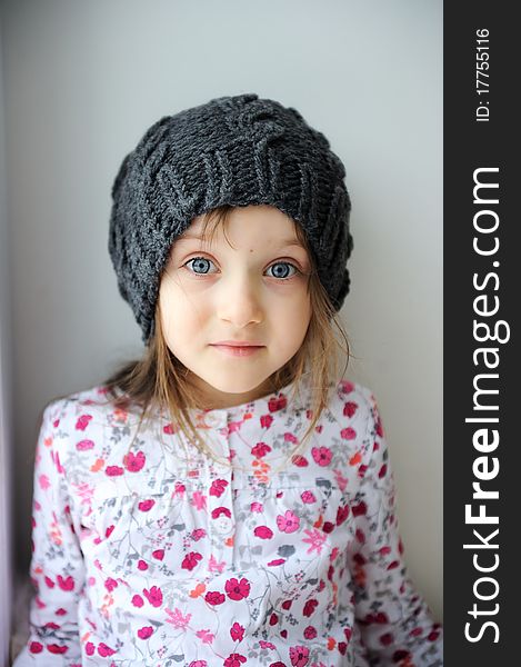 Adorable little kid girl with blue eyes in dark grey knit hat. Adorable little kid girl with blue eyes in dark grey knit hat