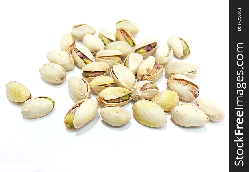 A heap of pistachio nuts scattered on a white background.