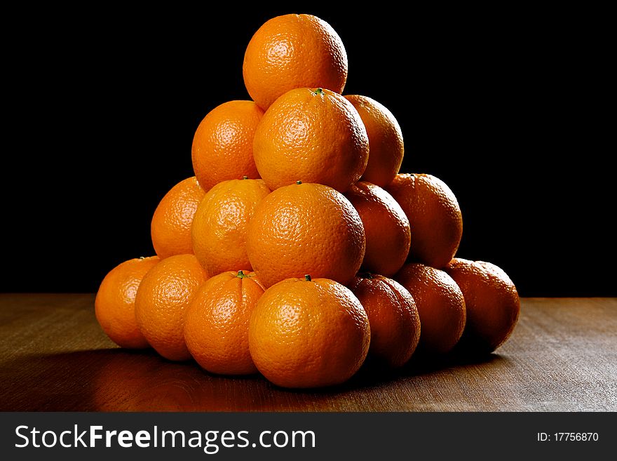Oranges on wooden table, against black background
