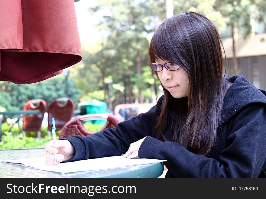 A Chinese girl who is a student, reading books on campus. She is studying hard for exam. A Chinese girl who is a student, reading books on campus. She is studying hard for exam.