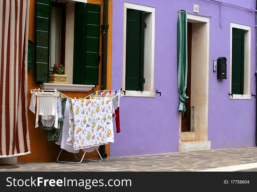 Clothes set out to dry in front of a colourful Burano home