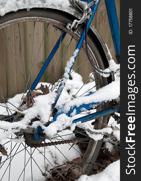 Old, blue bicycle standing in the snow