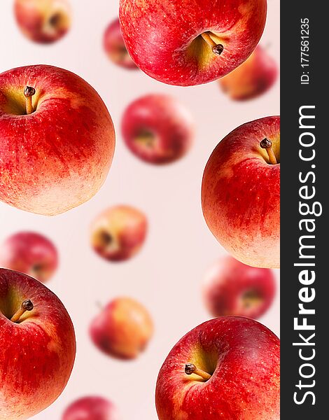 Large ripe red apples falling from top to bottom. Open composition. Close-up. Light pink background. Blurred perspective. Large ripe red apples falling from top to bottom. Open composition. Close-up. Light pink background. Blurred perspective.