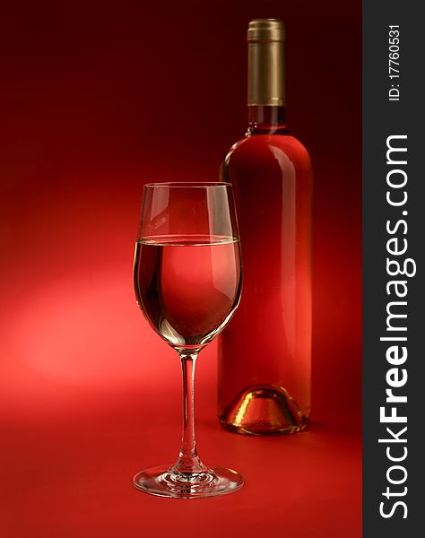 Bottle and glass of wine on a red background. Bottle and glass of wine on a red background